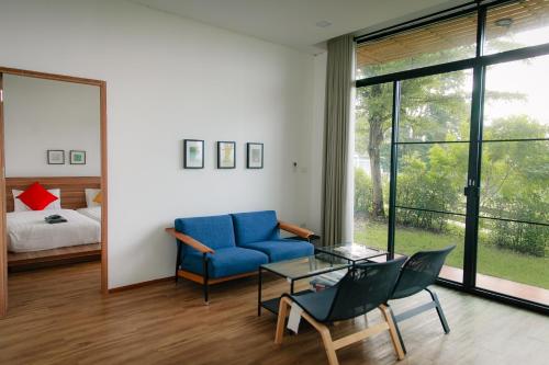呵叻的住宿－Baan Phu Pa Pha บ้านภูปภา，客厅配有蓝色的沙发和玻璃桌