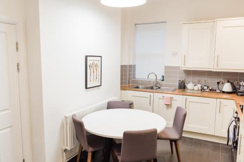a white kitchen with a white table and chairs at Edgbaston Park Hotel Birmingham in Birmingham