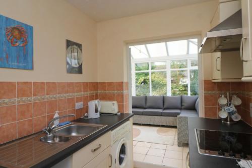 a kitchen with a sink and a couch at Holiday Bungalow, short drive to 7 Beaches! in St Merryn