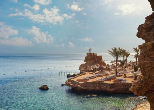 a beach with chairs and umbrellas and the ocean at Dreams Beach Resort - Sharm El Sheikh in Sharm El Sheikh