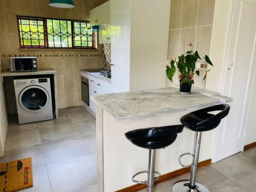 a kitchen with a counter and two stools at Garden and Park Leisure on Tugela in Benoni