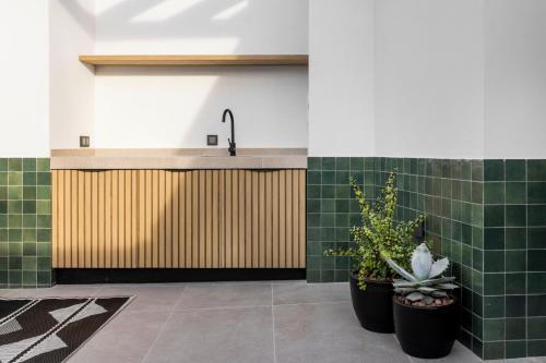 uma casa de banho com azulejos verdes, um lavatório e plantas em Doña Lola Alojamientos Boutique em Lucena