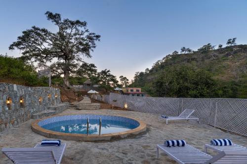 a swimming pool with two lounge chairs and a fence at Turban Nature Wilderness , Kumbhalgarh in Kumbhalgarh