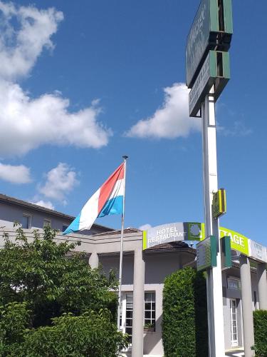 a flag flying in front of a building with a street sign at Cottage Logis Hôtel - Restaurant in Dudelange