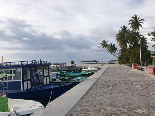 a boat parked next to a dock with palm trees at Chambao Maldives in Guraidhoo