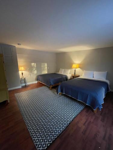 two beds in a room with a rug at Brookside Hideaway, Brook Road Inn in Goshen