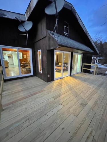 a house with a large wooden deck with windows at Brookside Hideaway, Brook Road Inn in Goshen