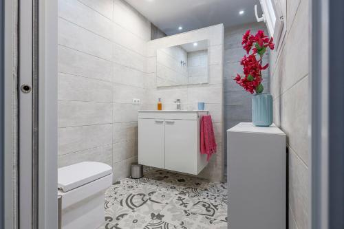 a bathroom with a toilet and a vase of flowers at Minimalismo de Vanguardia con altas calidades 1 BR in Seville