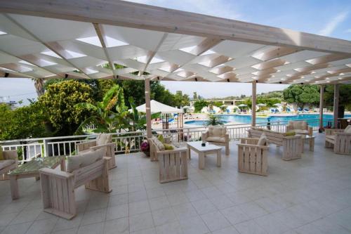 a patio with tables and chairs and a pool at Happy Days Hotel, Adults Only in Theologos