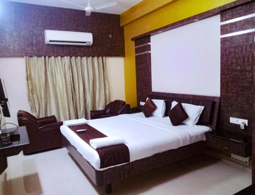 a bedroom with a bed with chairs at Pine Tree in Kanchipuram