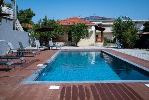 ein Swimmingpool mit Stühlen und ein Haus in der Unterkunft Elegant house by the sea with pool in Akráta