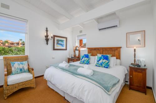 a bedroom with a large bed and a chair at San Lameer Villa 3115 - 4 Bedroom Classic - 8 pax - San Lameer Rental Agency in Southbroom