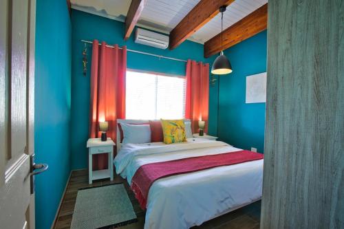 a bedroom with a bed with blue walls and a window at Coastal Soul no 1 in Swakopmund
