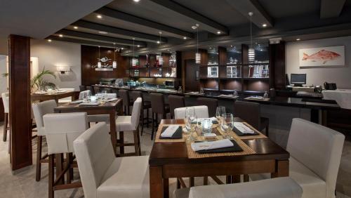 a restaurant with wooden tables and white chairs at Manchebo Beach Resort and Spa in Palm-Eagle Beach