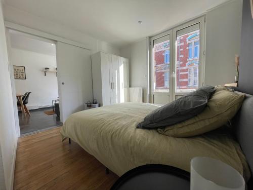 une chambre avec un grand lit et une fenêtre dans l'établissement Appartement Malouin - Villa Leopold, à Dunkerque