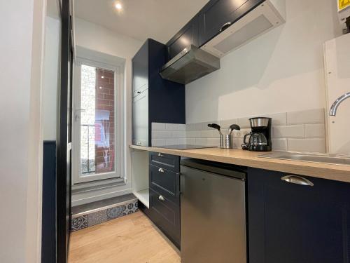 une cuisine avec des armoires bleues et un évier dans l'établissement Appartement Malouin - Villa Leopold, à Dunkerque