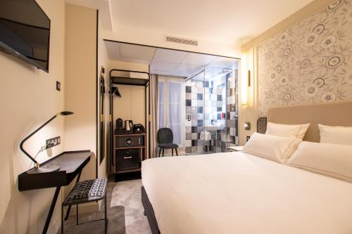 ein Hotelzimmer mit einem weißen Bett und einem Schreibtisch in der Unterkunft ELSA, Hôtel Paris in Paris