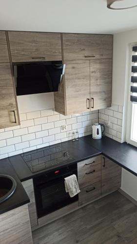 a kitchen with wooden cabinets and a black stove top oven at Apartament Zdrojowy in Głuchołazy