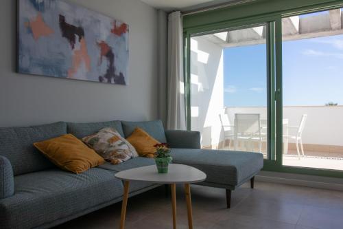 uma sala de estar com um sofá azul e uma mesa em Precioso apartamento frente a la playa con piscina em Mojácar