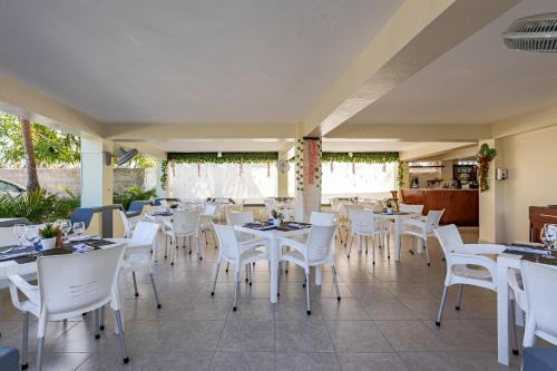 a restaurant with white tables and white chairs at Hotel Turístico Marian in Las Terrenas