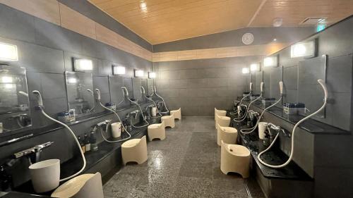 ein Bad mit einer Reihe von Urinalen und Waschbecken in der Unterkunft Capsule Hotel Topos Sendai Station Nishiguchi in Sendai