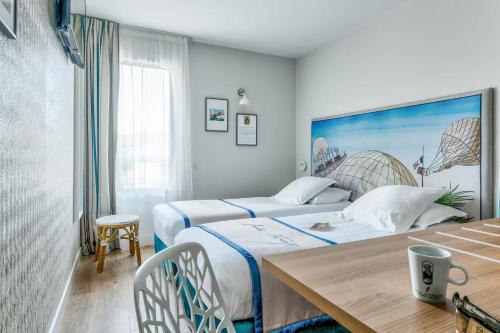 a hotel room with two beds and a table at Hôtel Jules Verne Biarritz in Biarritz