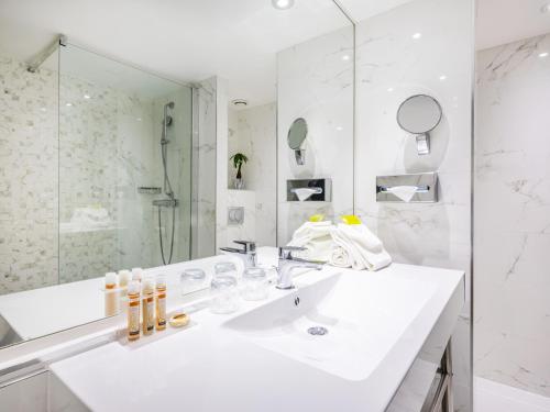 bagno bianco con lavandino e specchio di Hotel Nice Riviera a Nizza