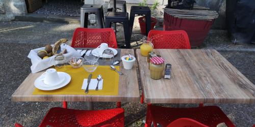 a wooden table with plates and utensils on it at Chambres d'Hôtes Le Mimosa in Saint-Saturnin-de-Lucian
