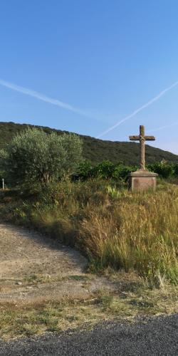 a cross on the side of a hill with a road at Chambres d'Hôtes Le Mimosa in Saint-Saturnin-de-Lucian