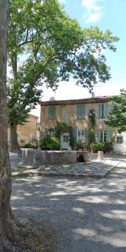 a house with a tree in front of it at Chambres d'Hôtes Le Mimosa in Saint-Saturnin-de-Lucian