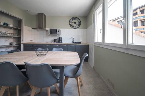 une cuisine avec une table, des chaises et une horloge dans l'établissement La cahute, appartement T2 avec jardin ou appartement familial T6, à Montauban