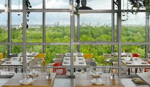 - un restaurant avec des tables, des chaises et de grandes fenêtres dans l'établissement 25hours Hotel Bikini Berlin, à Berlin