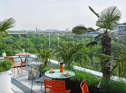 een patio met 2 tafels en stoelen op een balkon bij 25hours Hotel Bikini Berlin in Berlijn