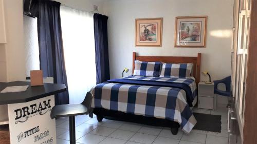 a bedroom with a bed with a blue and white blanket at 13th Avenue Guesthouse Benoni in Benoni