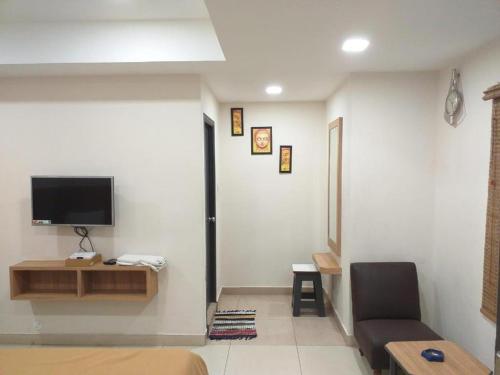 a living room with a couch and a tv on a wall at Sri Abbirami Lodge in Kumbakonam