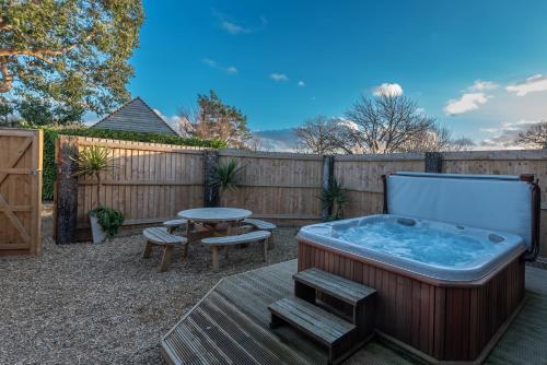 uma banheira de hidromassagem num quintal com uma mesa e cadeiras em Somerset Country Escape - Luxury barns with hot tubs em Hatch Beauchamp