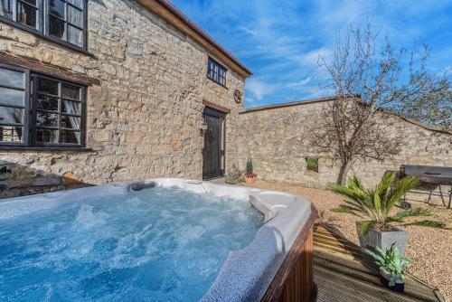 una bañera de hidromasaje en un patio junto a un edificio en Somerset Country Escape - Luxury barns with hot tubs, en Hatch Beauchamp