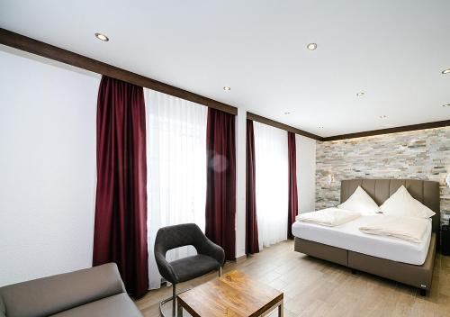 a bedroom with a bed and a chair at Central City Hotel in Füssen