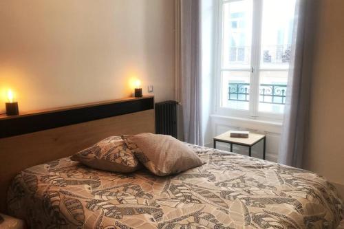 um quarto com uma cama com duas almofadas e uma janela em Le Louvre Auvergnat em Royat