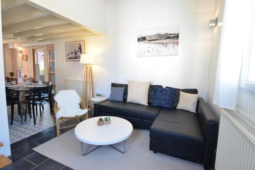 un salon avec un canapé noir et une table dans l'établissement Duplex Voltaire Modern Apartment - 3 bedrooms - citycenter and beach - WIFI, à Biarritz
