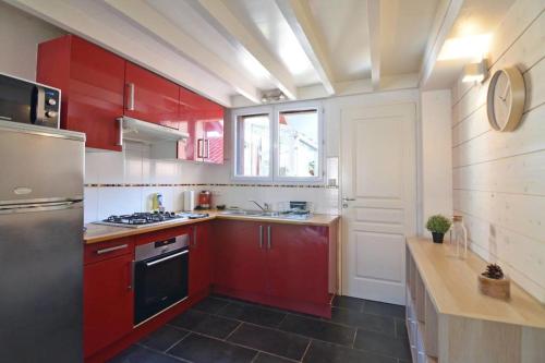 - une cuisine avec des placards rouges et une cuisinière noire dans l'établissement Duplex Voltaire Modern Apartment - 3 bedrooms - citycenter and beach - WIFI, à Biarritz