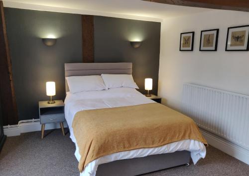 a bedroom with a large bed with two lamps on tables at The Fox in Much Wenlock