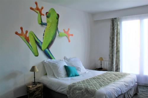 1 dormitorio con 1 cama con una rana en la pared en Au Palmyre Hôtel en La Palmyre