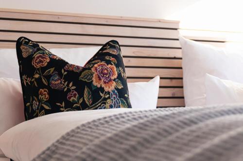 a black pillow sitting on a bed with white pillows at Walser ART in Mittelberg
