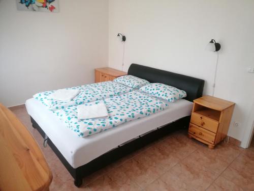 ハイドゥソボスローにあるSzabo Laszlo Apartmanのベッド(青と白のシーツ、木製のナイトスタンド付)