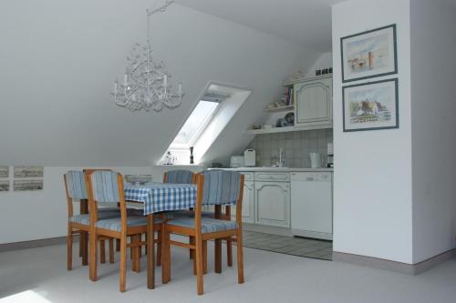 une cuisine avec une table et des chaises ainsi qu'un lustre dans l'établissement Haus Burmeister, à Tinnum