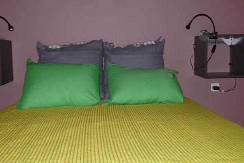 a bed with green and gray pillows on it at Nice Apartment Near City Center in Athens