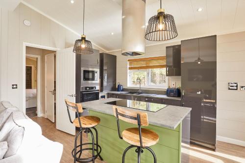 a kitchen with a green island with two bar stools at Host & Stay - Eller Beck, The Cabin In The Woods in Egton