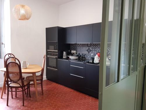 une cuisine avec des armoires noires et une table avec des chaises dans l'établissement Appartement CLADA/ Côté Lac, à Ajaccio
