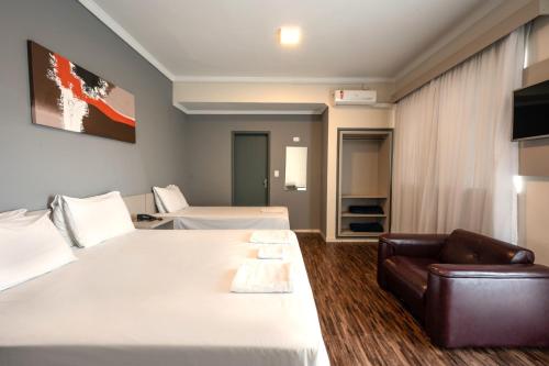 um quarto de hotel com duas camas e um sofá em Italian Palace Hotel Rede Carlton em Três Corações